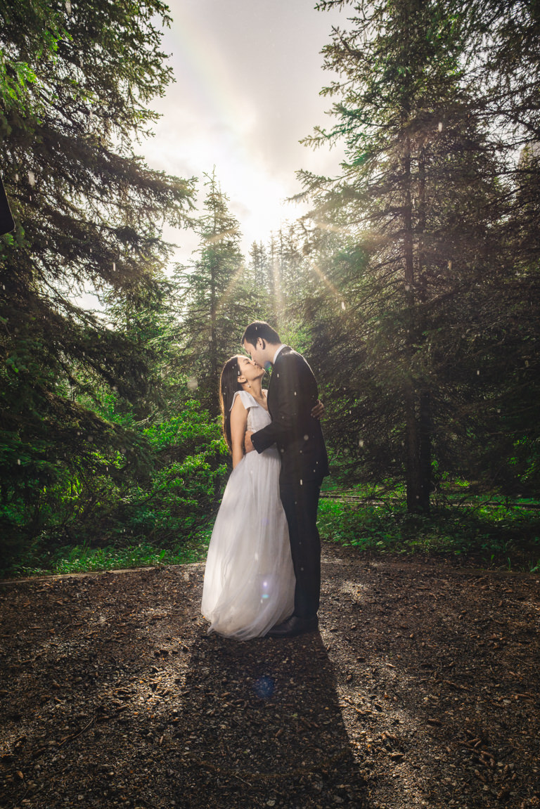 bride and groom at moraine lake with rainbow in sky