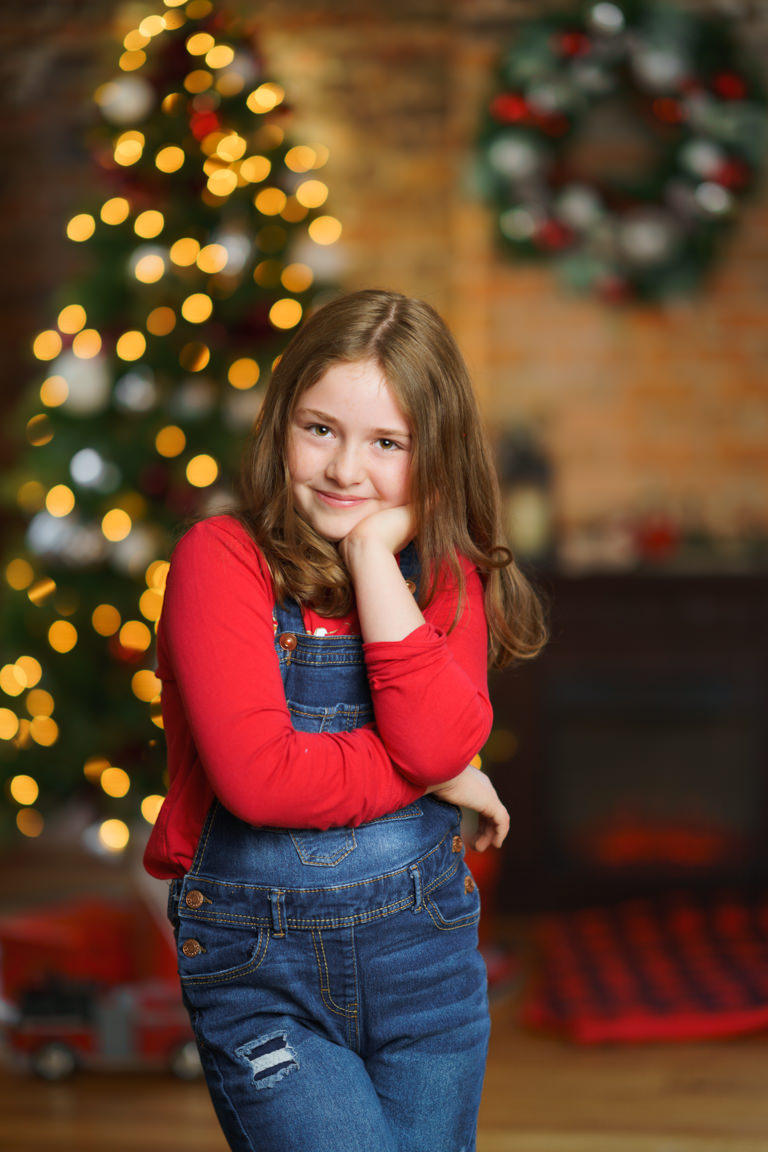 young girl posing in front of Christmas tree