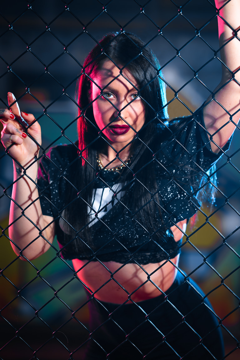 model posing behind fence with graffiti